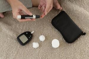 Close up of woman checking blood sugar level by using Digital Glucose meter, health care, medicine, diabetes, glycemia concept photo