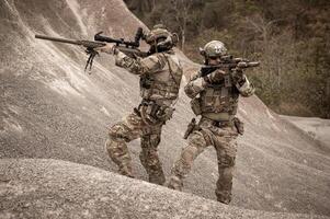 soldados en camuflaje uniformes puntería con su rifles listos a fuego durante militar operación en el Desierto soldados formación en un militar operación foto