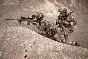 Soldiers in camouflage uniforms aiming with their riflesready to fire during military operation in the desert soldiers training  in a military operation photo