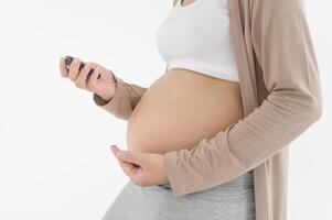 Pregnant woman checking blood sugar level by using Digital Glucose meter, health care, medicine, diabetes, glycemia concept photo