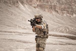 Soldiers in camouflage uniforms aiming with their riflesready to fire during military operation in the desert soldiers training  in a military operation photo