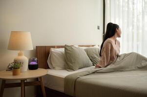 Young asian woman stretching in bed after Waking up in the Morning photo