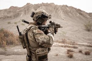 Soldiers in camouflage uniforms aiming with their riflesready to fire during military operation in the desert soldiers training  in a military operation photo