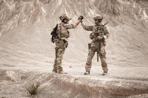 Soldiers in camouflage uniforms aiming with their riflesready to fire during military operation in the desert soldiers training  in a military operation photo