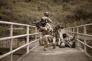 soldados en camuflaje uniformes puntería con su rifles listos a fuego durante militar operación en el bosque soldados formación en un militar operación foto
