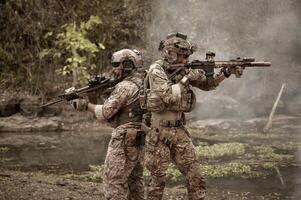 soldados en camuflaje uniformes puntería con su rifles listos a fuego durante militar operación en el bosque soldados formación en un militar operación foto