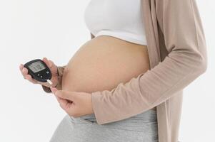 Pregnant woman checking blood sugar level by using Digital Glucose meter, health care, medicine, diabetes, glycemia concept photo