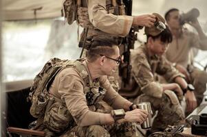 Soldiers in camouflage uniforms planning on operation in the camp, soldiers training in a military operation photo