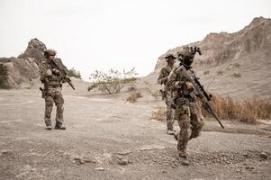 Soldiers in camouflage uniforms aiming with their riflesready to fire during military operation in the desert soldiers training in a military operation photo