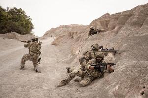 Soldiers in camouflage uniforms aiming with their riflesready to fire during military operation in the desert soldiers training in a military operation photo