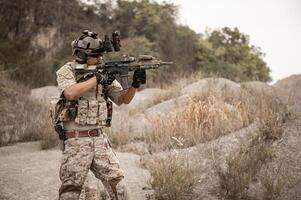 Soldiers in camouflage uniforms aiming with their riflesready to fire during military operation in the desert soldiers training in a military operation photo