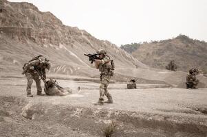 Soldiers in camouflage uniforms aiming with their riflesready to fire during military operation in the desert soldiers training in a military operation photo