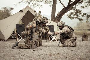 Soldiers in camouflage uniforms planning on operation in the camp, soldiers training in a military operation photo