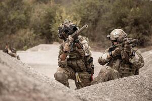 Soldiers in camouflage uniforms aiming with their riflesready to fire during military operation in the desert soldiers training in a military operation photo