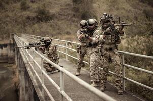 soldados en camuflaje uniformes puntería con su rifles listos a fuego durante militar operación en el bosque soldados formación en un militar operación foto