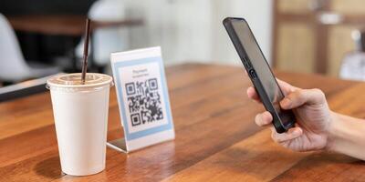 mujer utilizar teléfono inteligente a escanear qr código para orden menú en café restaurante con un digital entrega. escoger menú y orden acumular descuento. mi billetera, tecnología, pagar en línea, crédito tarjeta, banco aplicación foto