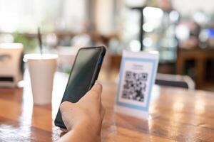 el hombre usa un teléfono inteligente para escanear el código qr para pagar en un café restaurante con un pago digital sin efectivo. elige menú y ordena acumula descuento. billetera electrónica, tecnología, pago en línea, tarjeta de crédito, aplicación bancaria. foto