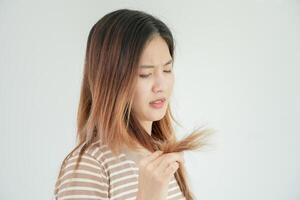 Asian woman very sad and upset looking at damaged hair, hair loss, hair thinning problem, vitamin deficiency, baldness, postpartum, biotin, zinc, menstrual or endocrine disorders, hormonal imbalance photo