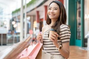 Modern happy asian Female lifestyle fashion portrait. beautiful attractive young woman girl enjoy stylish walk with shopping bag packages use smartphone on the street, trendy outfit on shopping mall photo