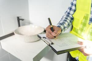 el inspector o ingeniero está inspeccionando la construcción y el aseguramiento de la calidad de la nueva casa usando una lista de verificación. ingenieros o arquitectos o contratistas trabajan para construir la casa antes de entregársela al propietario foto