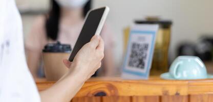 Woman use smartphone to scan QR code for order menu in cafe restaurant with a digital delivery. Choose menu and order accumulate discount. E wallet, technology, pay online, credit card, bank app. photo