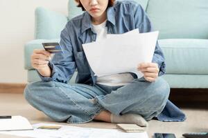 Stressed and headache asian woman with large bills or invoices no money to pay to expenses and credit card debt. shortage, Financial problems, mortgage, loan, bankruptcy, bankrupt, poor, empty wallet photo