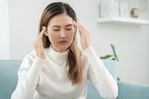 Headache, female having migraine pain, bad health, Asian woman feeling stress and headache, Office syndrome, sad tired touching forehead having migraine or depression, irritated girl, sadness grief photo