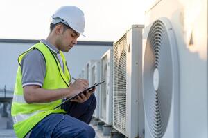 Asian maintenance engineer works on the roof of factory. contractor inspect compressor system and plans installation of air condition systems in construction. Checklist, inspector, control photo