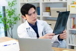 Photo of young Asian male doctor working at office