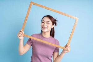 joven asiático mujer participación foto marco en azul antecedentes