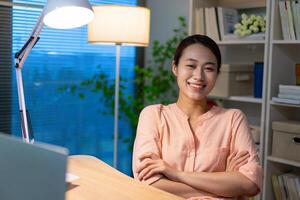 joven asiático mujer de negocios trabajando tarde noche a hogar foto