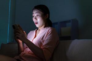 Young Asian woman using phone in the dark at night photo