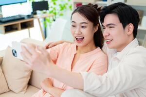 Photo of young Asian couple at home