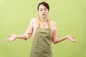 Photo of young Asian female housekeeper on green background