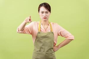 Photo of young Asian female housekeeper on green background