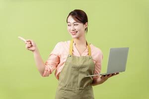 Photo of young Asian female housekeeper on green background