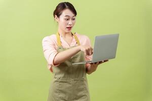 Photo of young Asian female housekeeper on green background