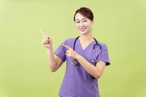 Photo of young Asian femle doctor on green background