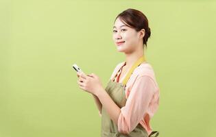 Photo of young Asian female housekeeper on green background