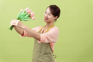 Photo of young Asian female housekeeper on green background