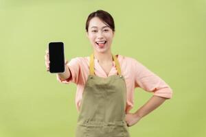 Photo of young Asian female housekeeper on green background