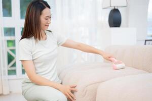 Young Asian woman cleaning sofa photo