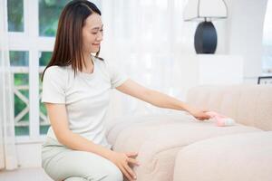 Young Asian woman cleaning sofa photo