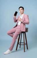 Photo of young Asian businessman wearing pink suit on background