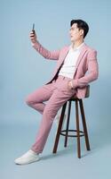 Photo of young Asian businessman wearing pink suit on background