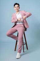 Photo of young Asian businessman wearing pink suit on background