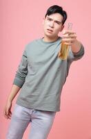 Photo of young Asian man drinking alcohol on background