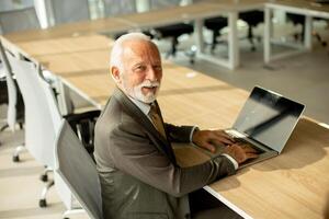 Senior businessman working on laptop computer in office photo