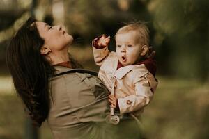 joven mujer participación linda bebé niña en el otoño parque foto