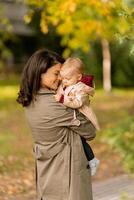 Young woman holding cute baby girl in the autumn park photo